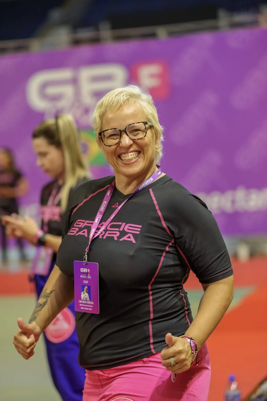 Profª Carla sorrindo com a camiseta da Gracie Barra em um evento